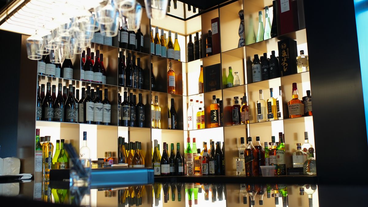 A backlit wall of bottles behind the bar