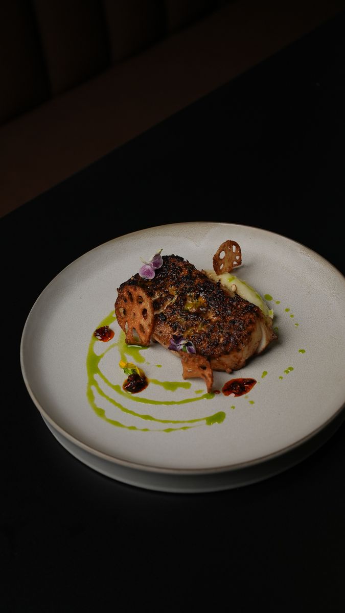 A seared fillet with a green sauce on a white plate
