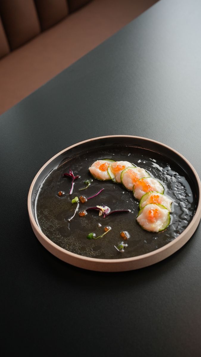 Shrimp in a line over a dark sauce on a round plate