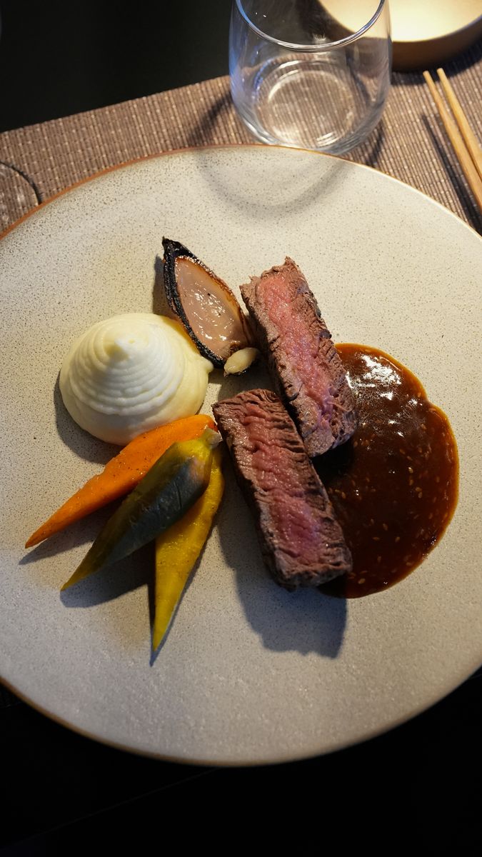 A plated steak with potato and jus