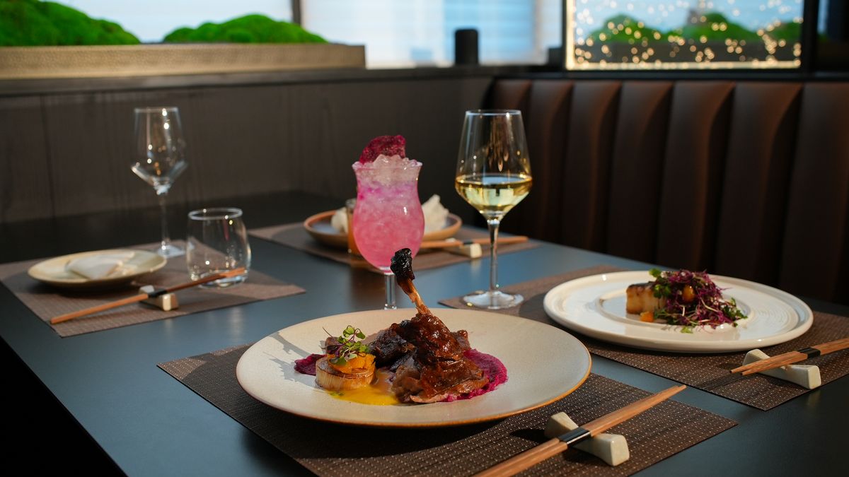 A table set with plates, wine and a pink cocktail