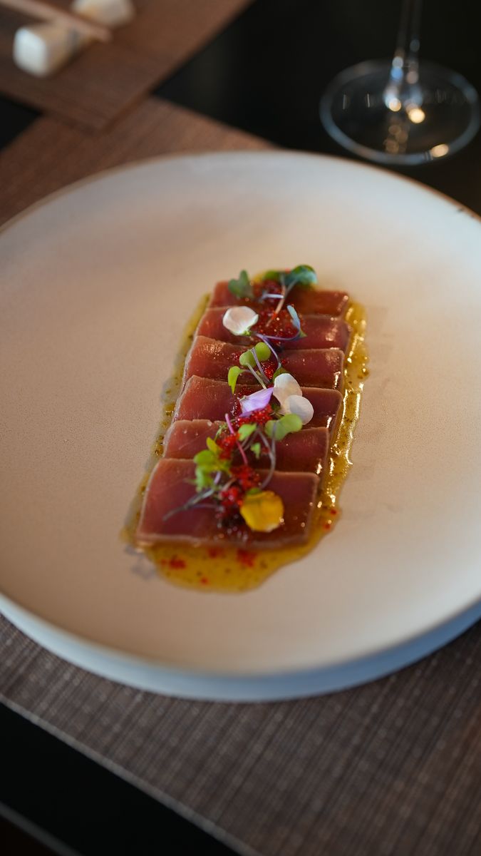 Tuna crudo with herbs on a white plate